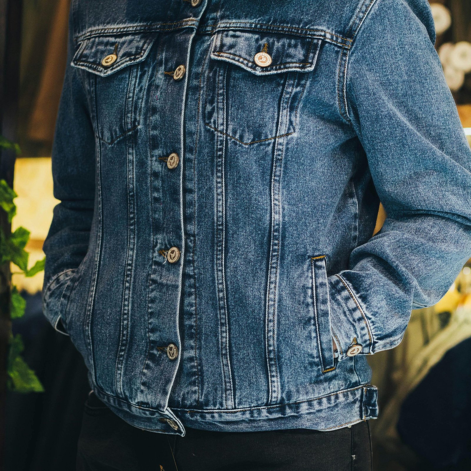 Man wearing a stylish denim jacket with white shearling collar, hands in pockets.
